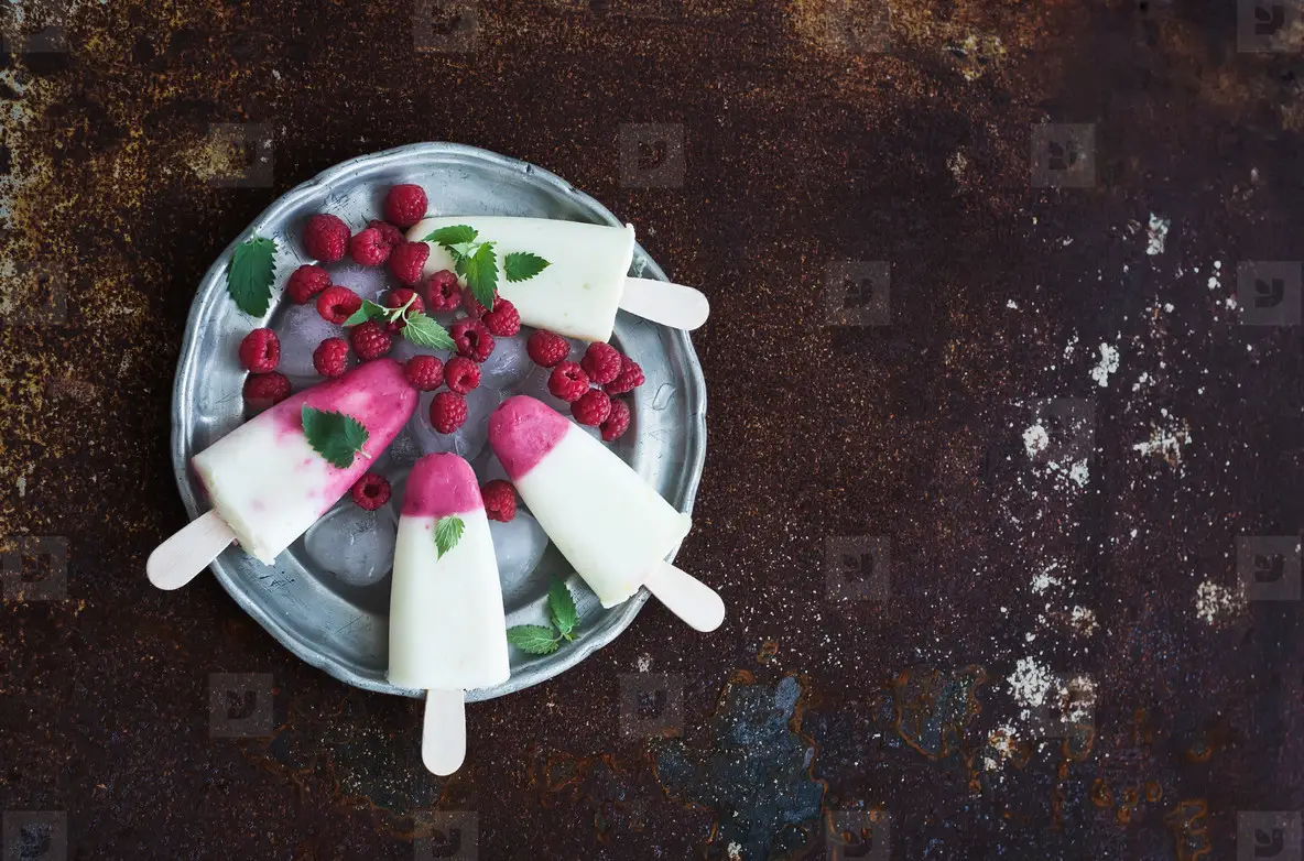 Raspberry lime yougurt ice creams or popsicles with fresh berries and ice cubeson