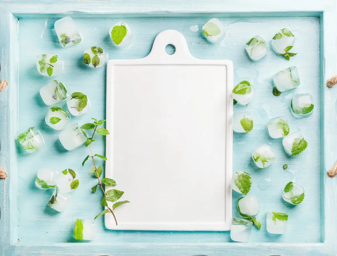 Ice cubes with frozen mint leaves inside in blue Turquoise tray and white ceramic board in center  copy space