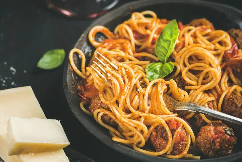 Spaghetti with meatballas, basil, parmesan cheese in black plate