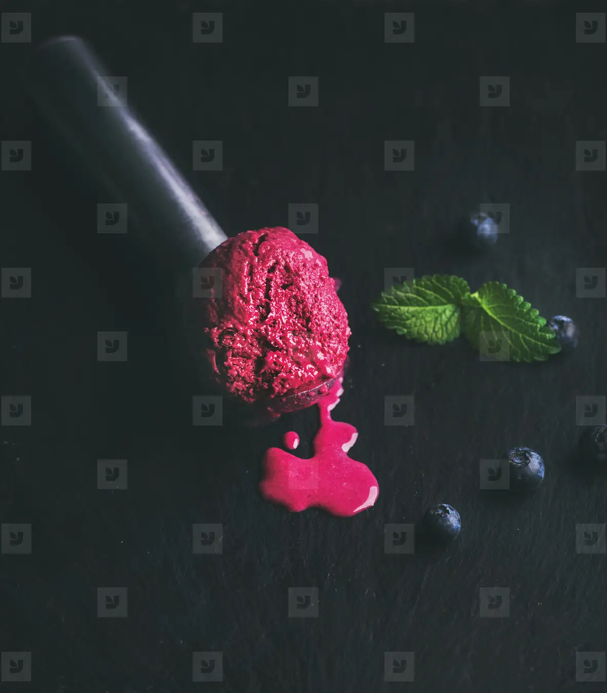 Melting scoop of blueberry ice cream with mint leaves