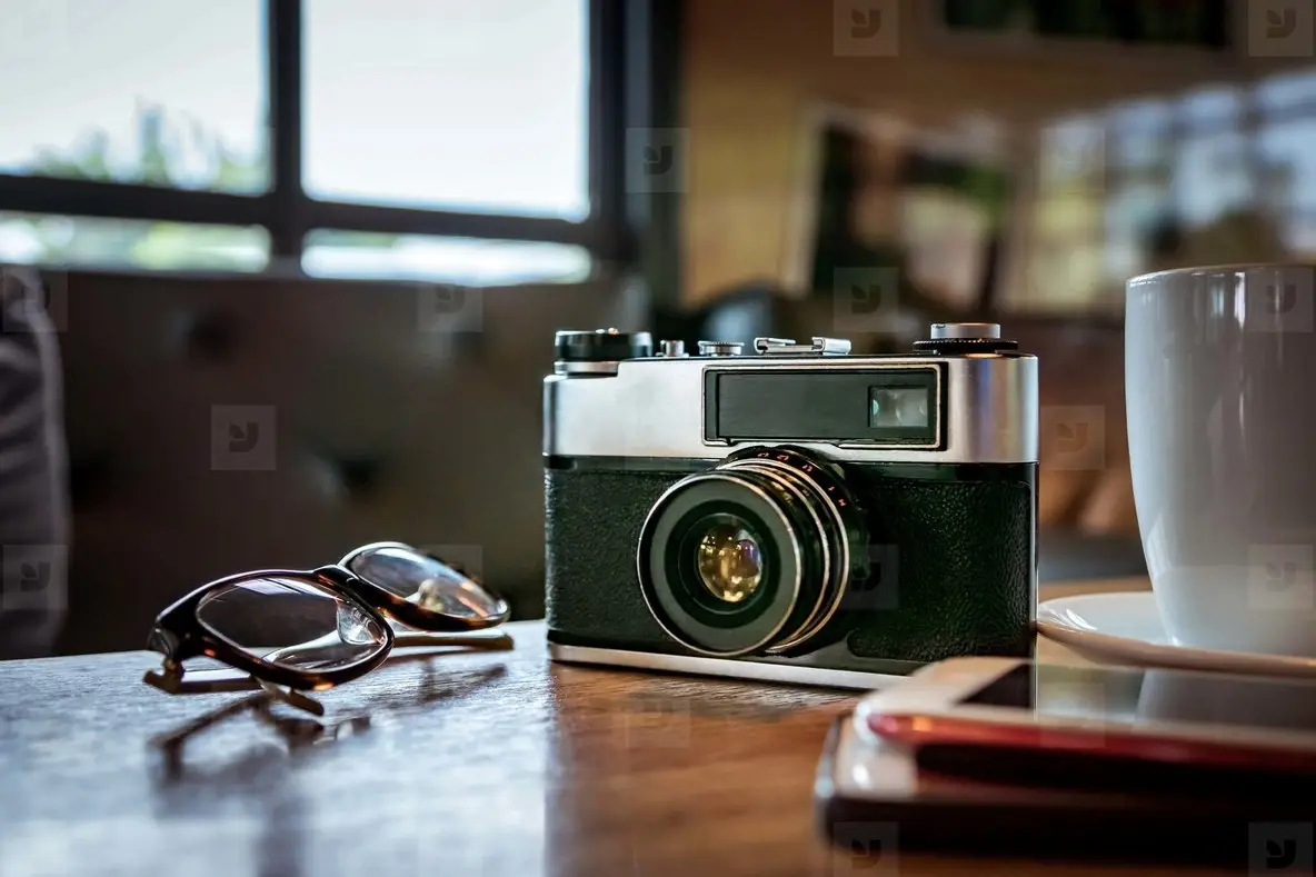 Vintage camera with coffee cup  glasses and smartphone on the ta