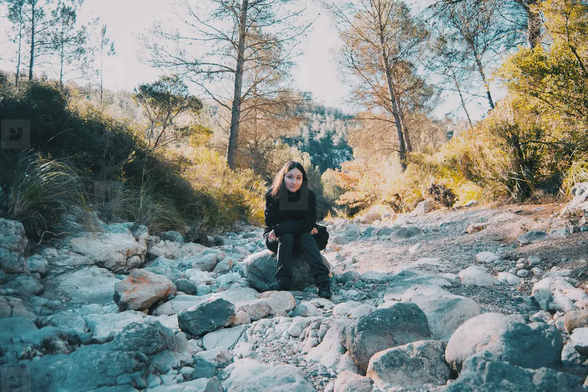 Girl Looking Over Rocks Smiling Girl Looking At Camera Sitting On A Rock On A Stone Path Photo ...