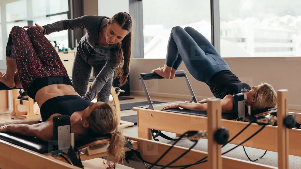 Female Pilates Trainer Helping A Pilates Woman During Training Photo (150487) - YouWorkForThem