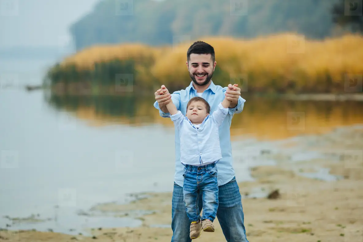 Dad holding infant sons hands