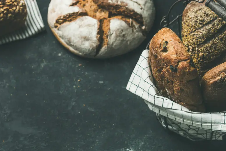 Various bread loaves on grey concrete background, copy space