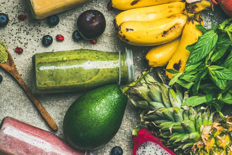 Colorful smoothies in bottles with fresh tropical fruit, square crop