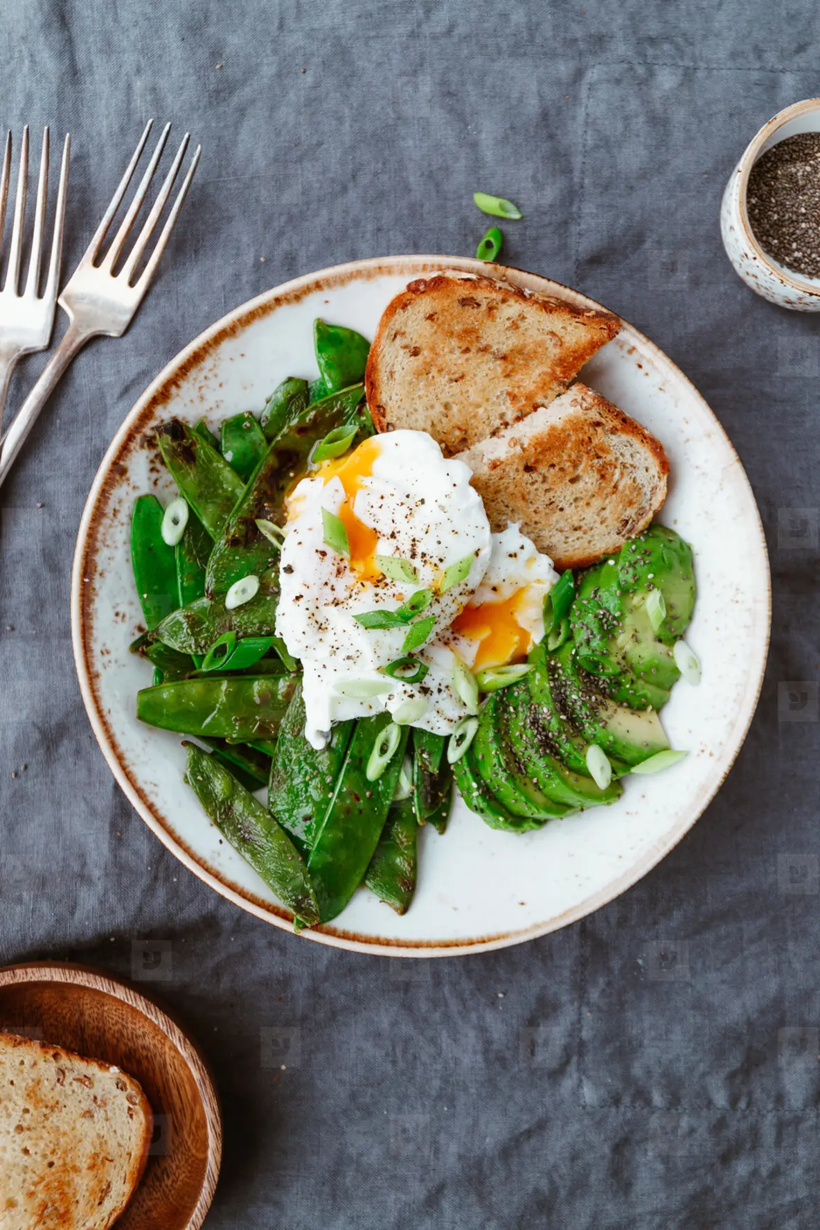 Top view of healthy breakfast or lunch  Fried snow peas  avocado  poached eggs are sprinkled chia seeds with toasts