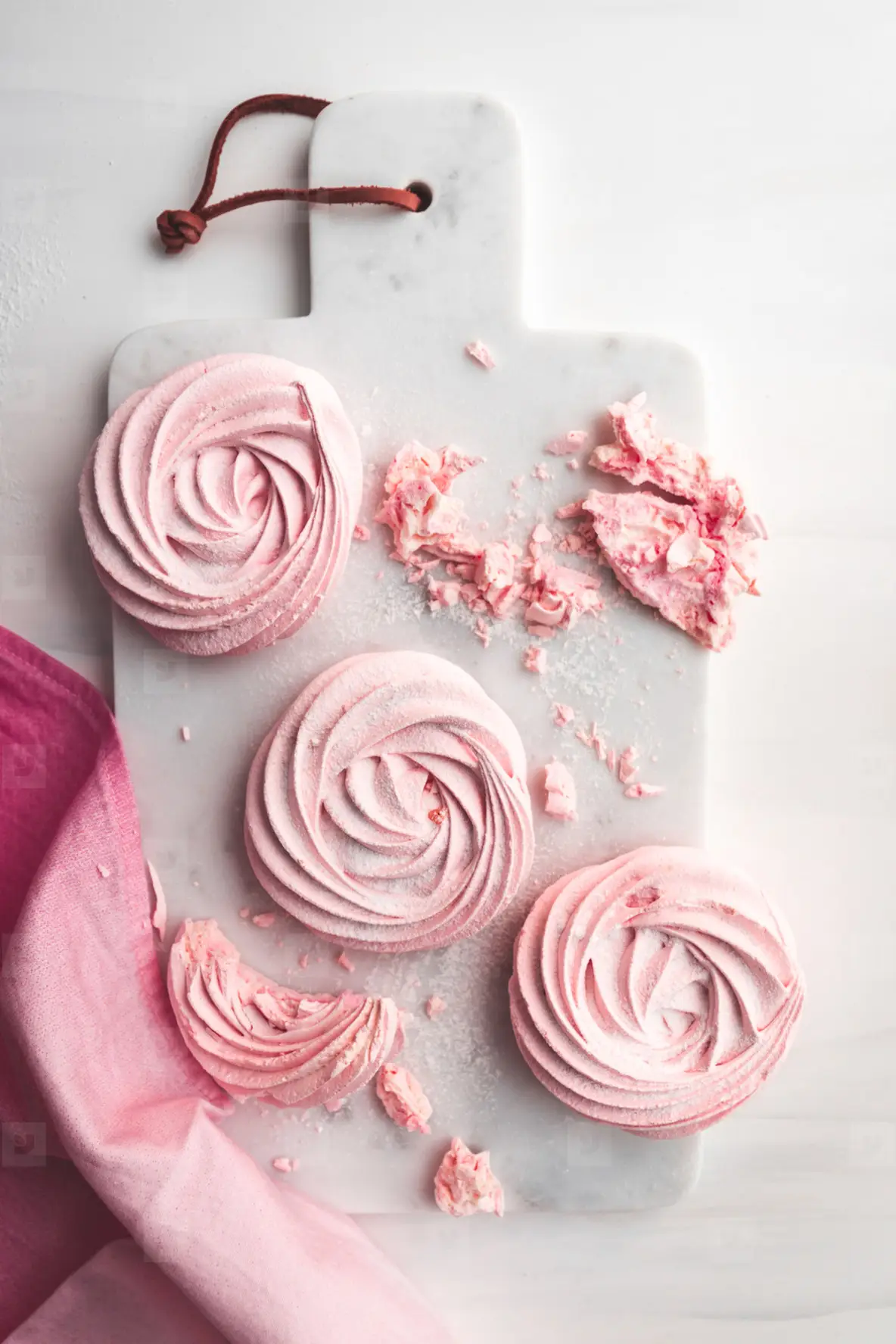 Top view of pink meringue on a white marble tray  Flat lay composition