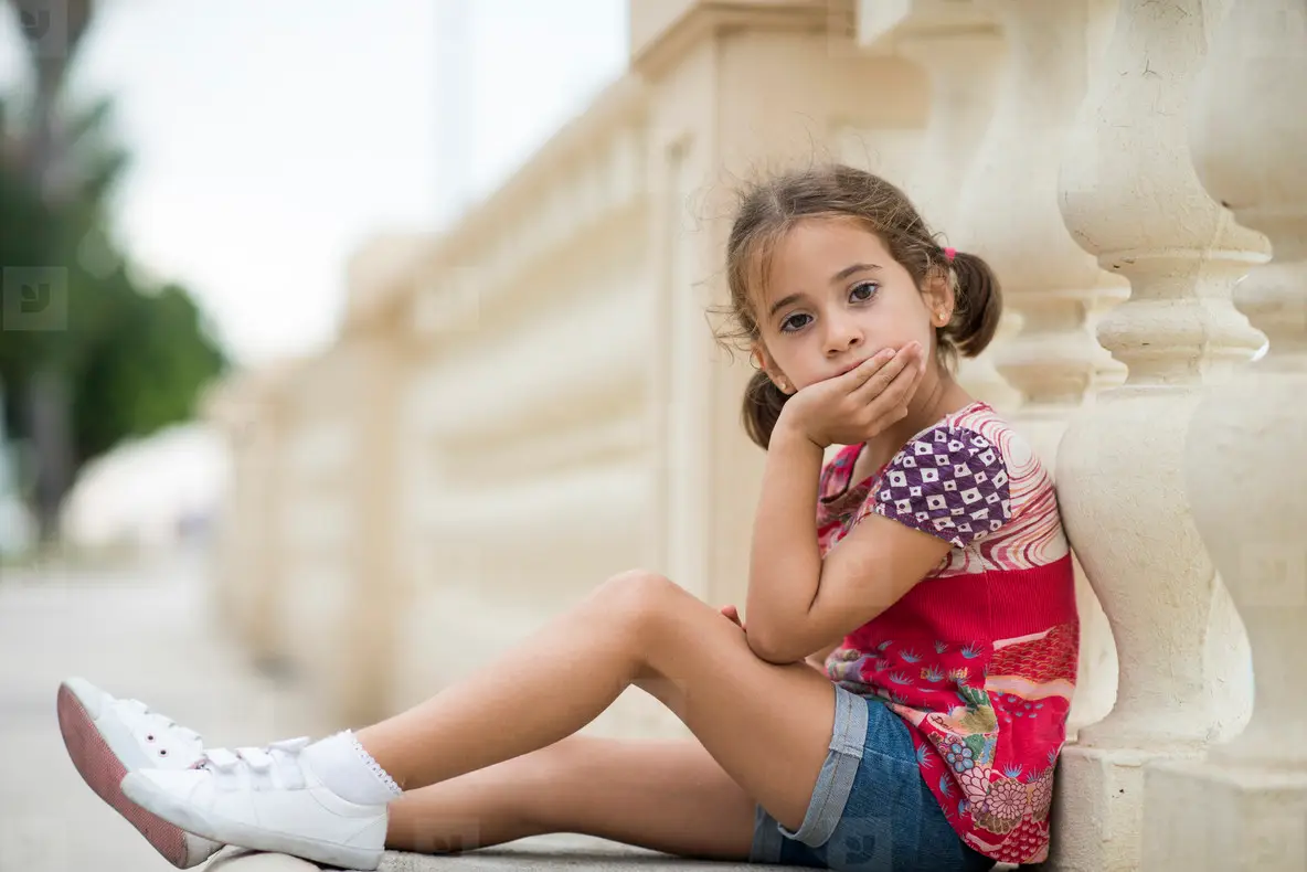 Adorable little girl combed with pigtails sitting on floor