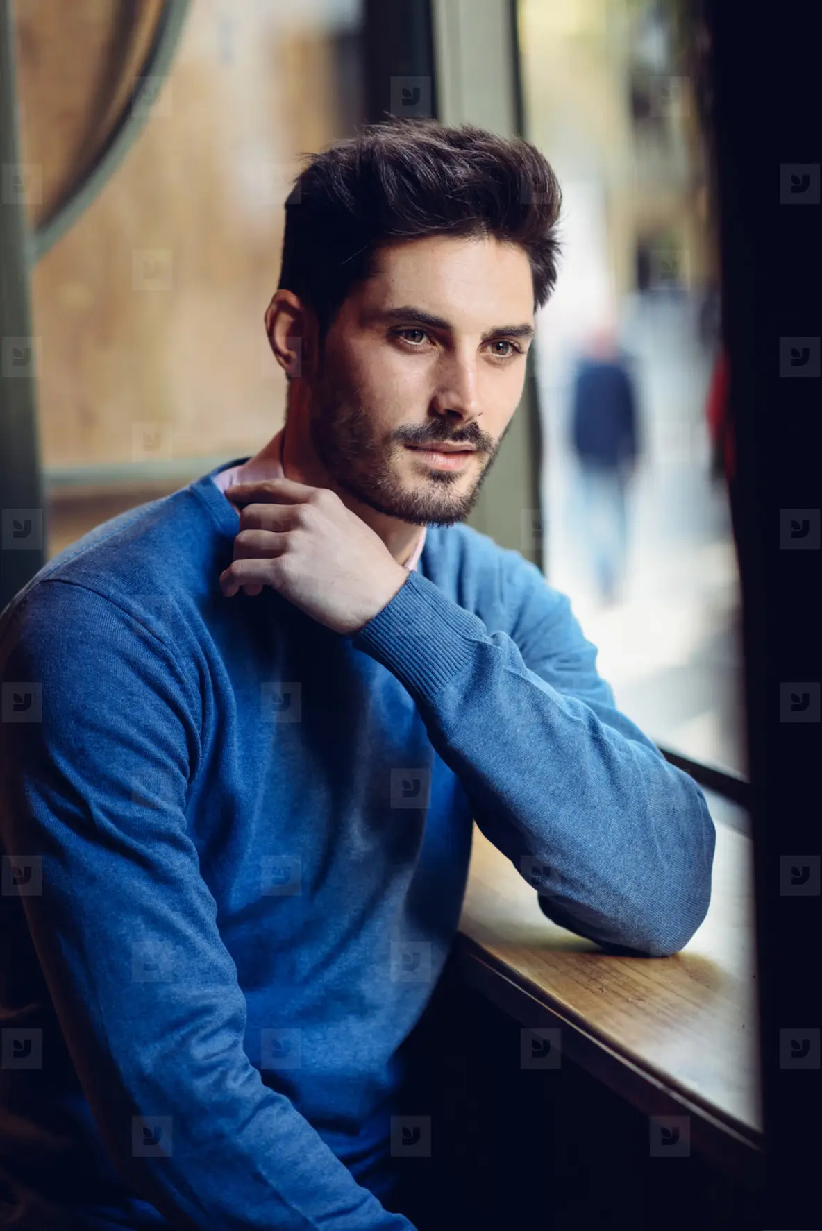 Pensive man with blue sweater with lost look near a window