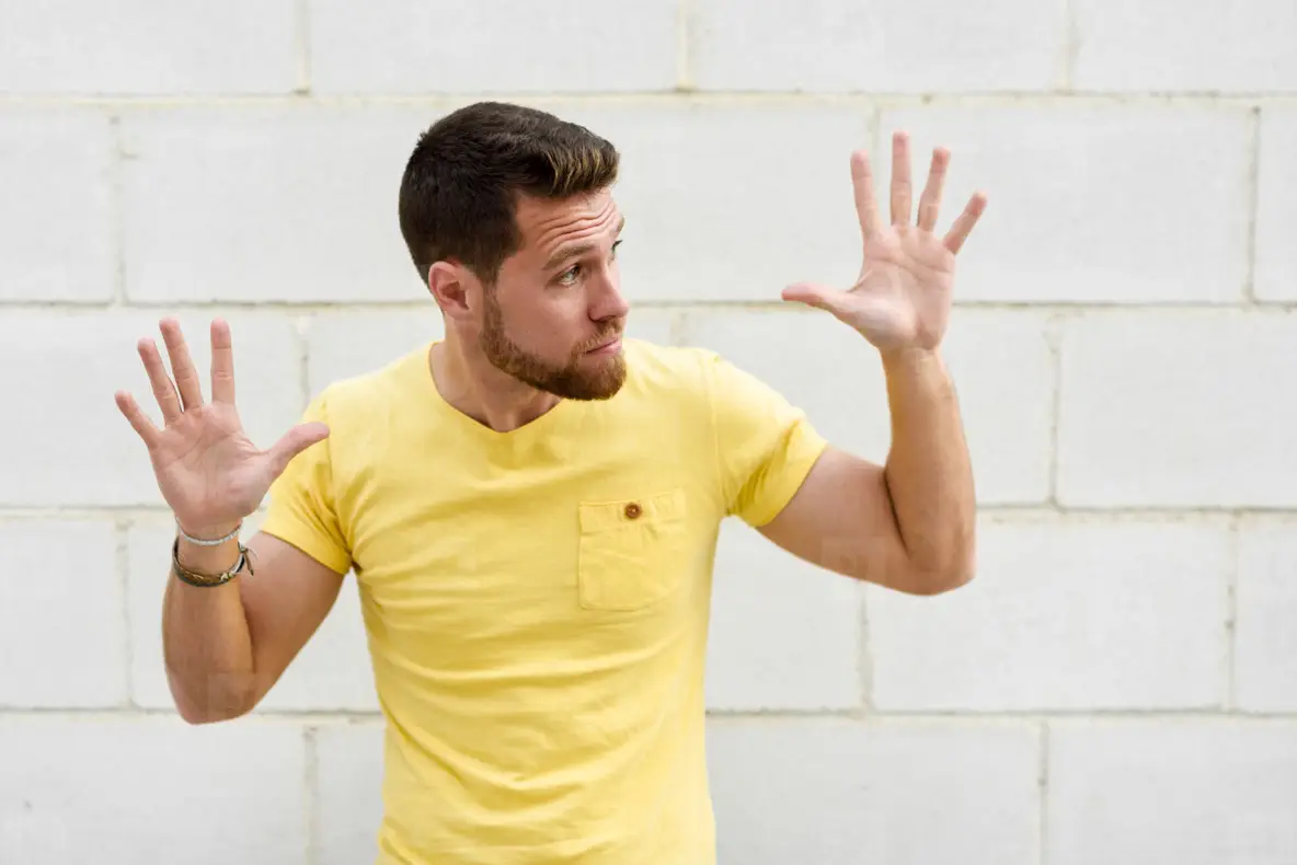 Funny young man on brick wall with open hands looking at rightsi