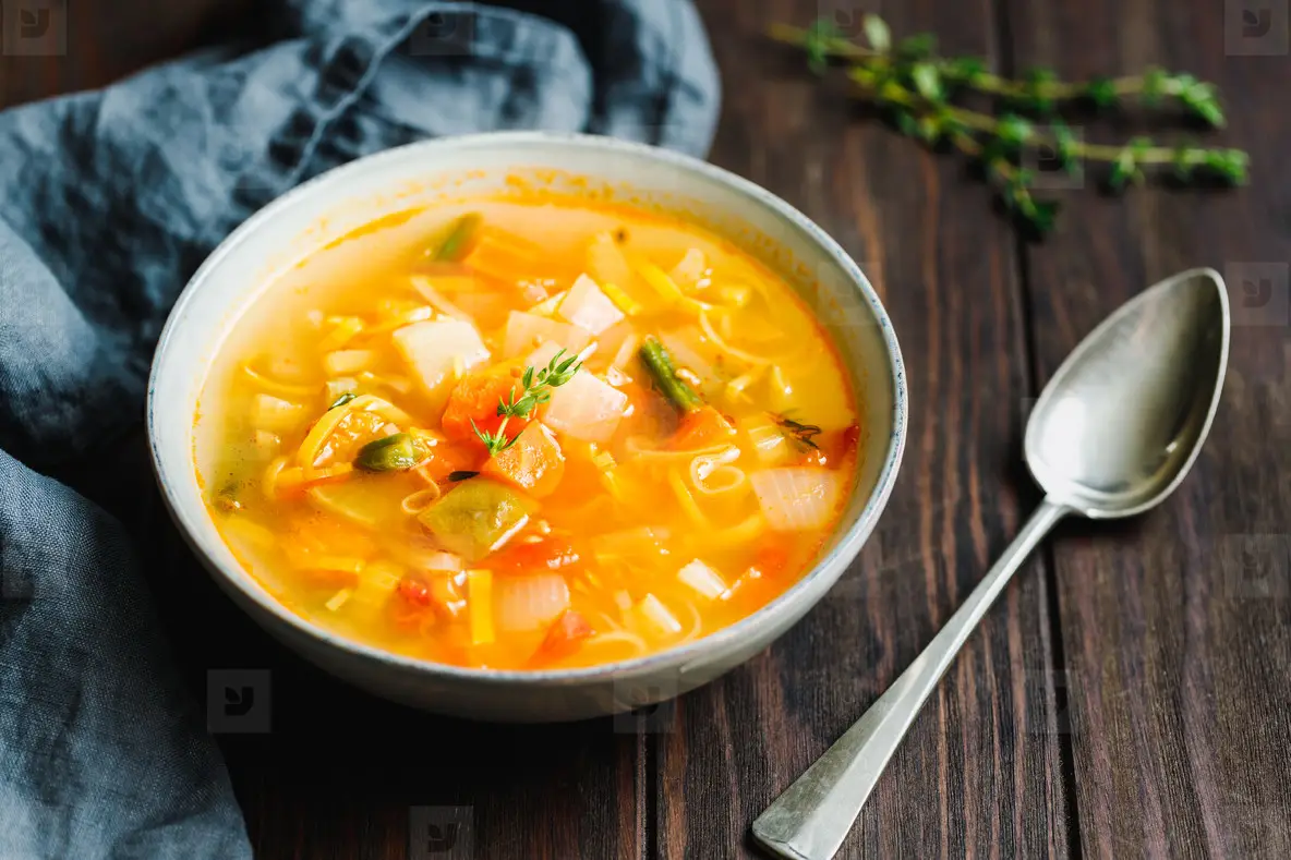 Spring vegetable soup with chicken stock for one person on wooden table  Rustic style  close up view