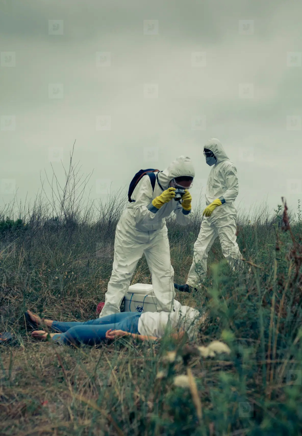 Man and woman in bacteriological protective suit taking a photo of a corpse