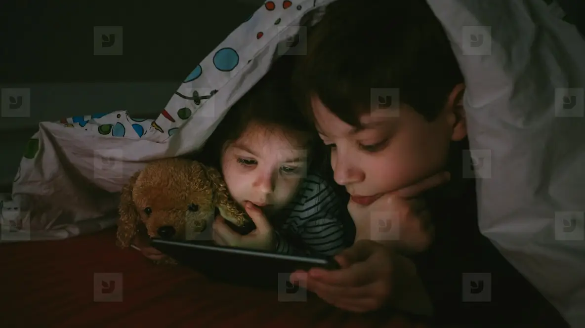 Brothers looking at the tablet in the dark