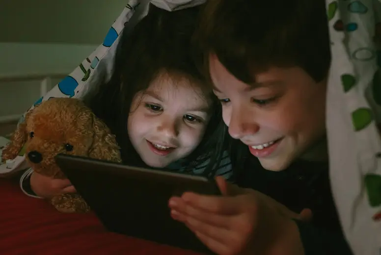 Brothers looking at the tablet in the dark