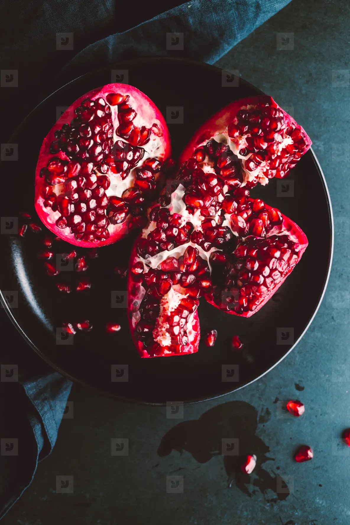 Top down view on a ripe pomegranate in a black plate on a dark background  Dark food photography