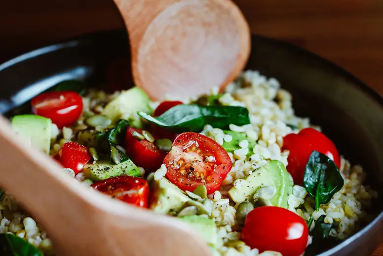 Healthy salad with bulgur, avocado, spinach and cherry tomatoes.