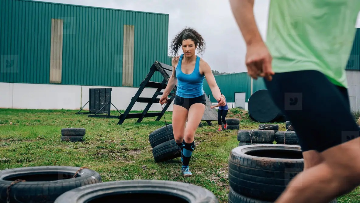 Participant in an obstacle course dragging wheels