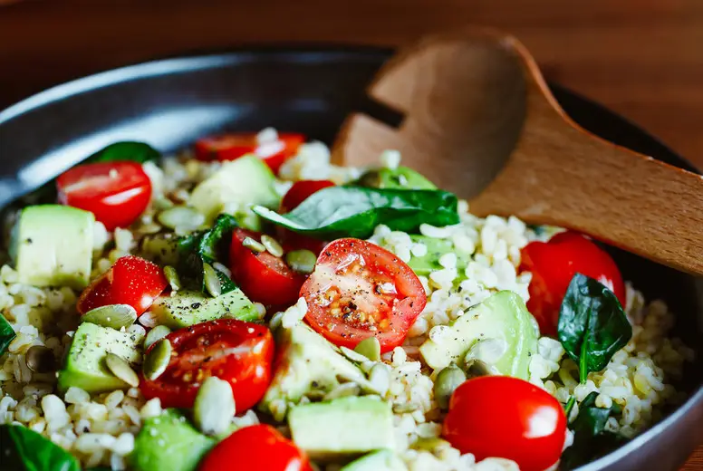 Healthy salad with bulgur, avocado, spinach and cherry tomatoes.
