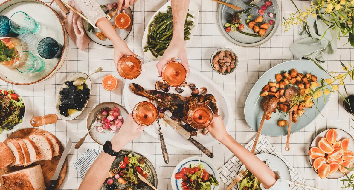Peoples hands clikning with wineglasses over table with snacks