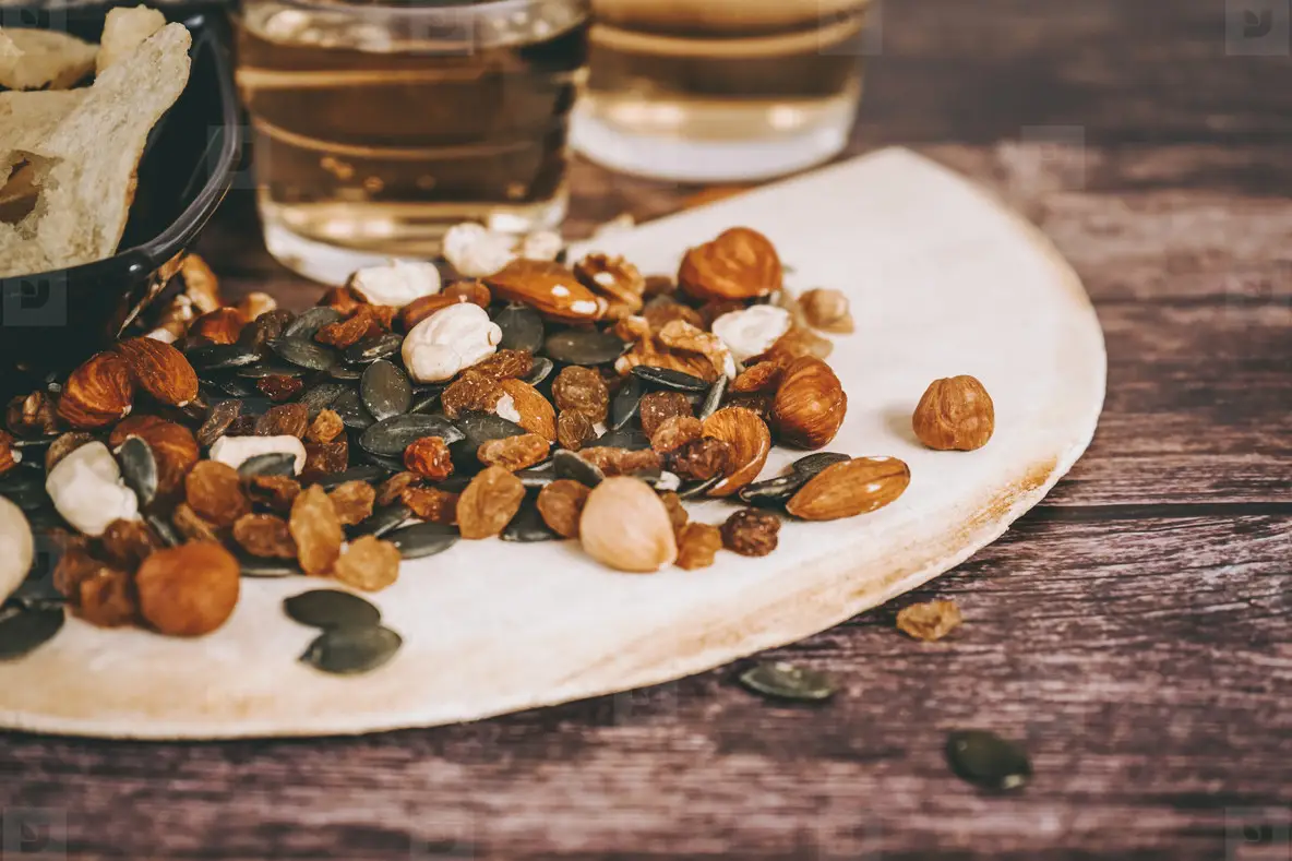 Mix of snacks with chips  nuts  seeds and beer