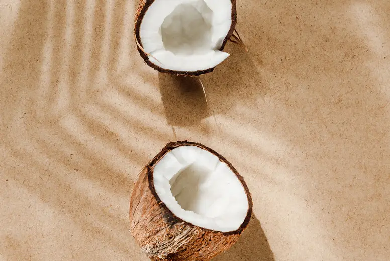Summer abstract creative composition with coconut a on wooden tray over kraft paper.