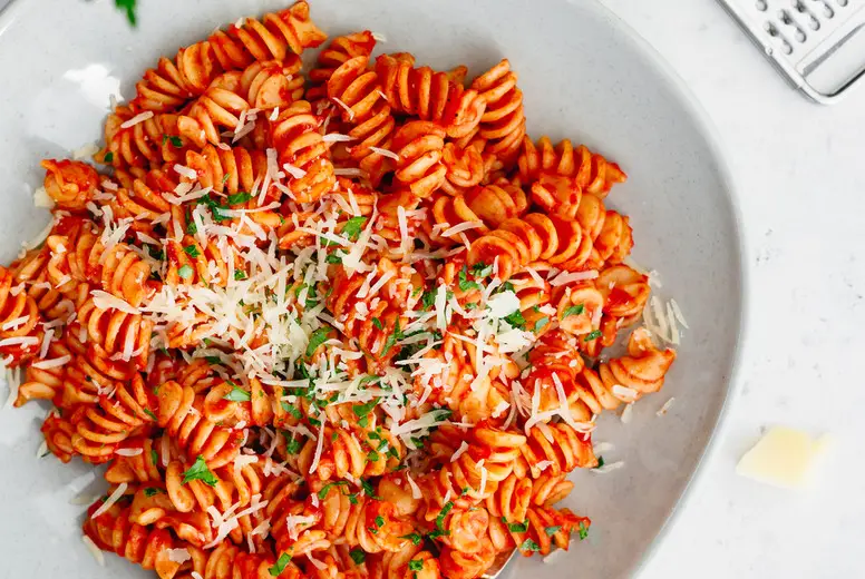 Top view of fusilli pasta with tomato sauce and parmesan cheese.