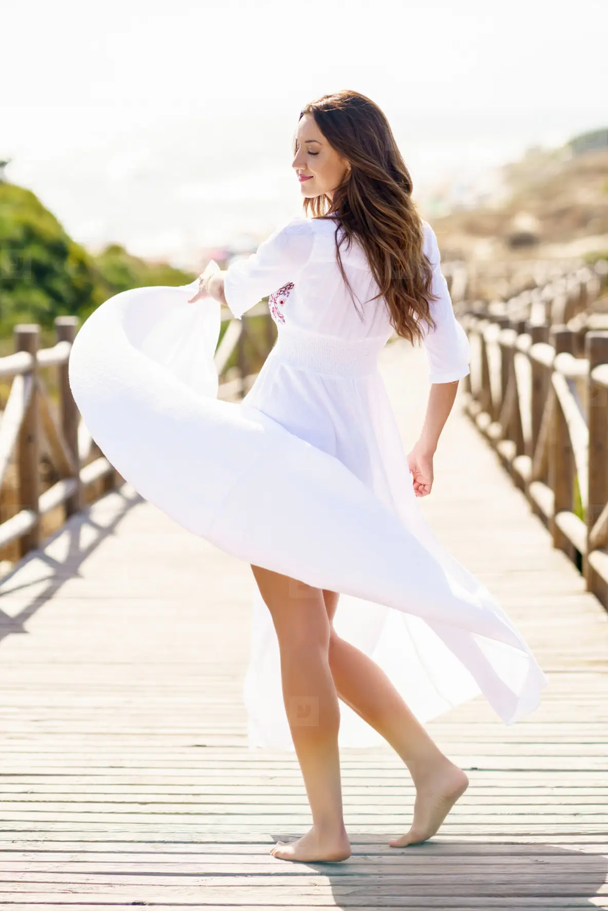 Young Woman Wearing A Beautiful White Dress in Spanish Fashion On A Boardwalk On The Beach Photo