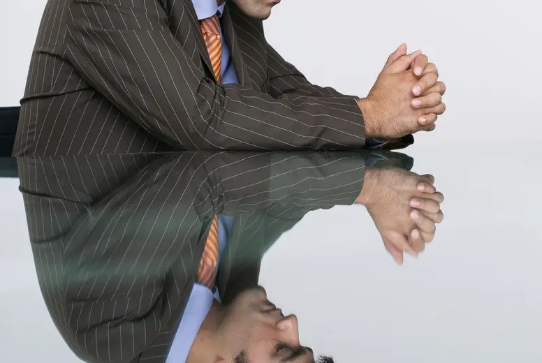 Reflection of thoughtful businessman in conference room table