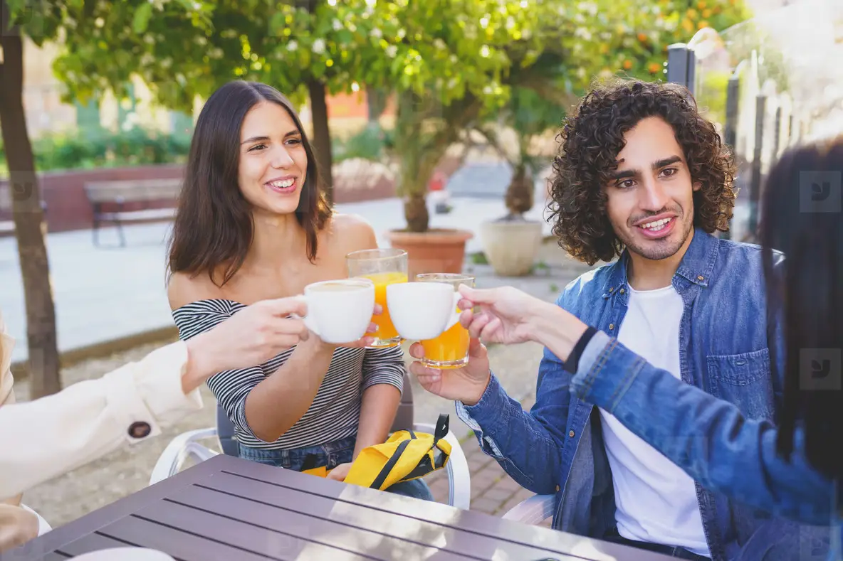Multi ethnic group of friends toasting with their drinks while having a drink together