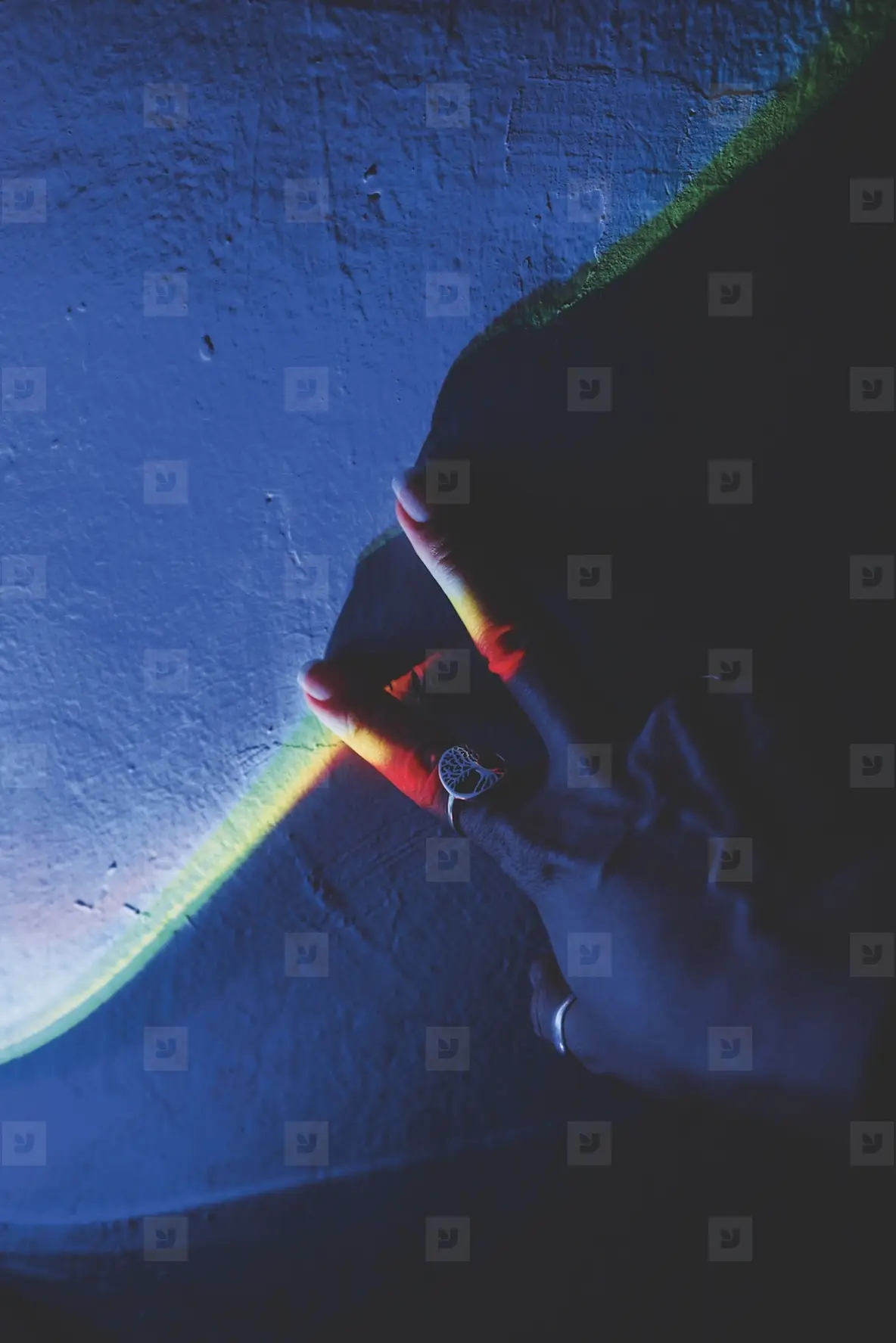 Detail of human hands illuminated by colorful lights