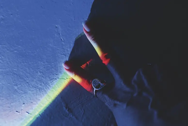 Detail of human hands illuminated by colorful lights