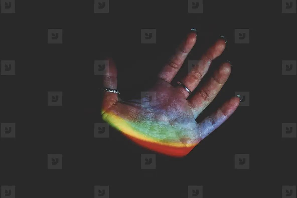 Detail of human hands illuminated by colorful lights