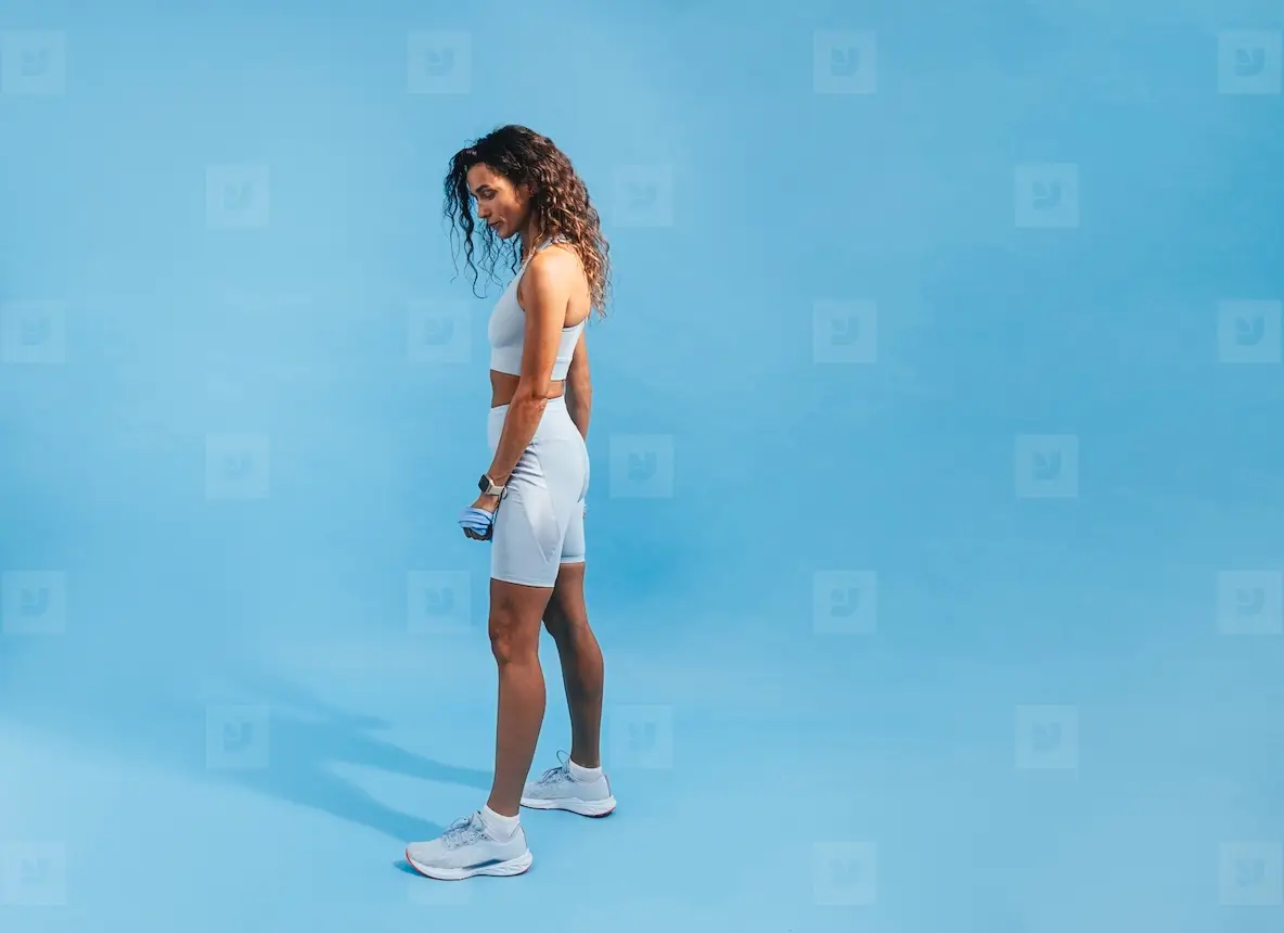 Fit woman posing on blue background  Side view of young sports woman relaxing