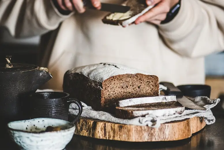 Woman having breakfast with rye Swedish bread and butter