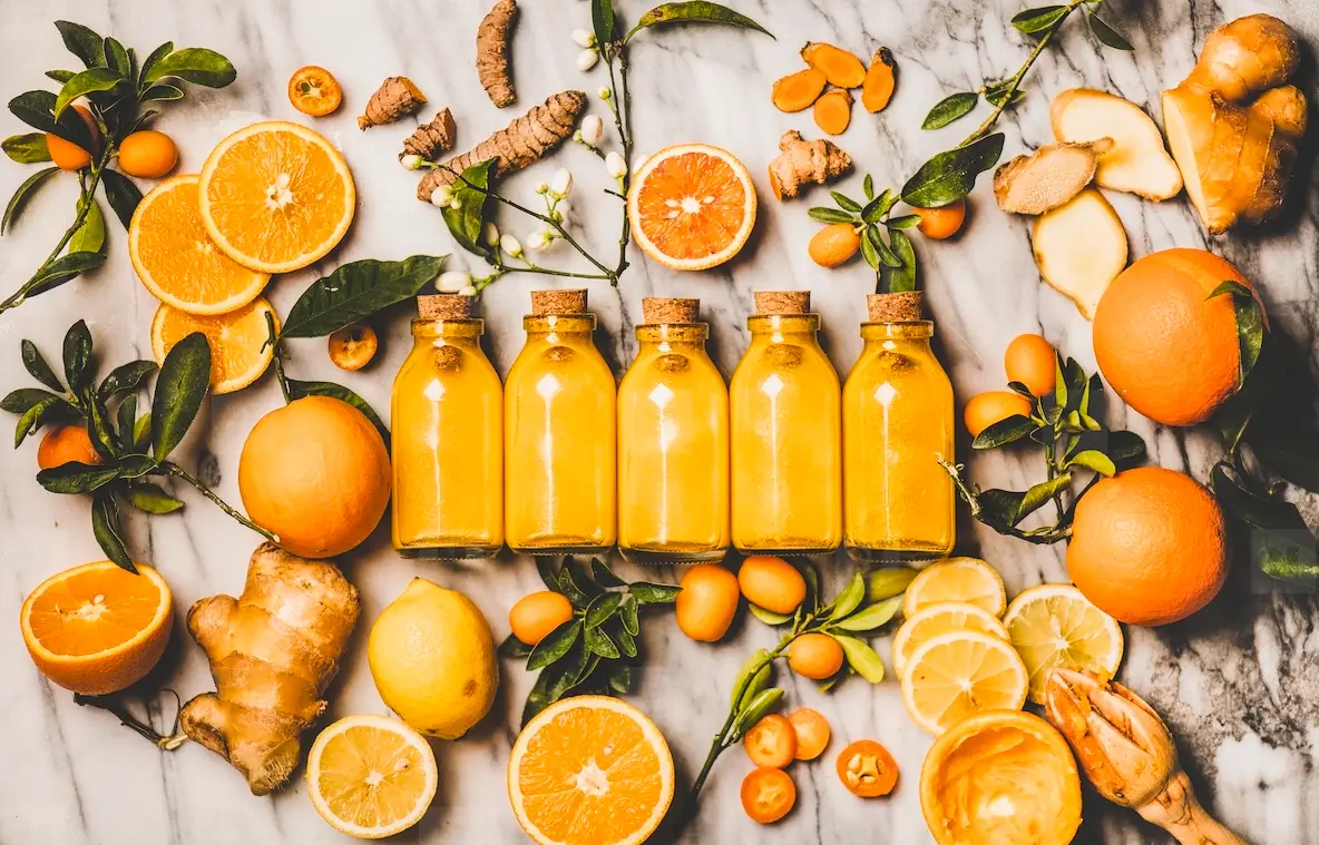 Turmeric  ginger  citrus juice shot in bottles over marble background