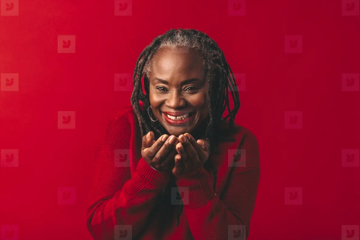 Mature woman blowing air confetti in a studio