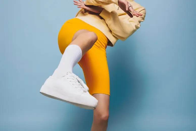 Energetic young woman winking at the camera while dancing in a studio