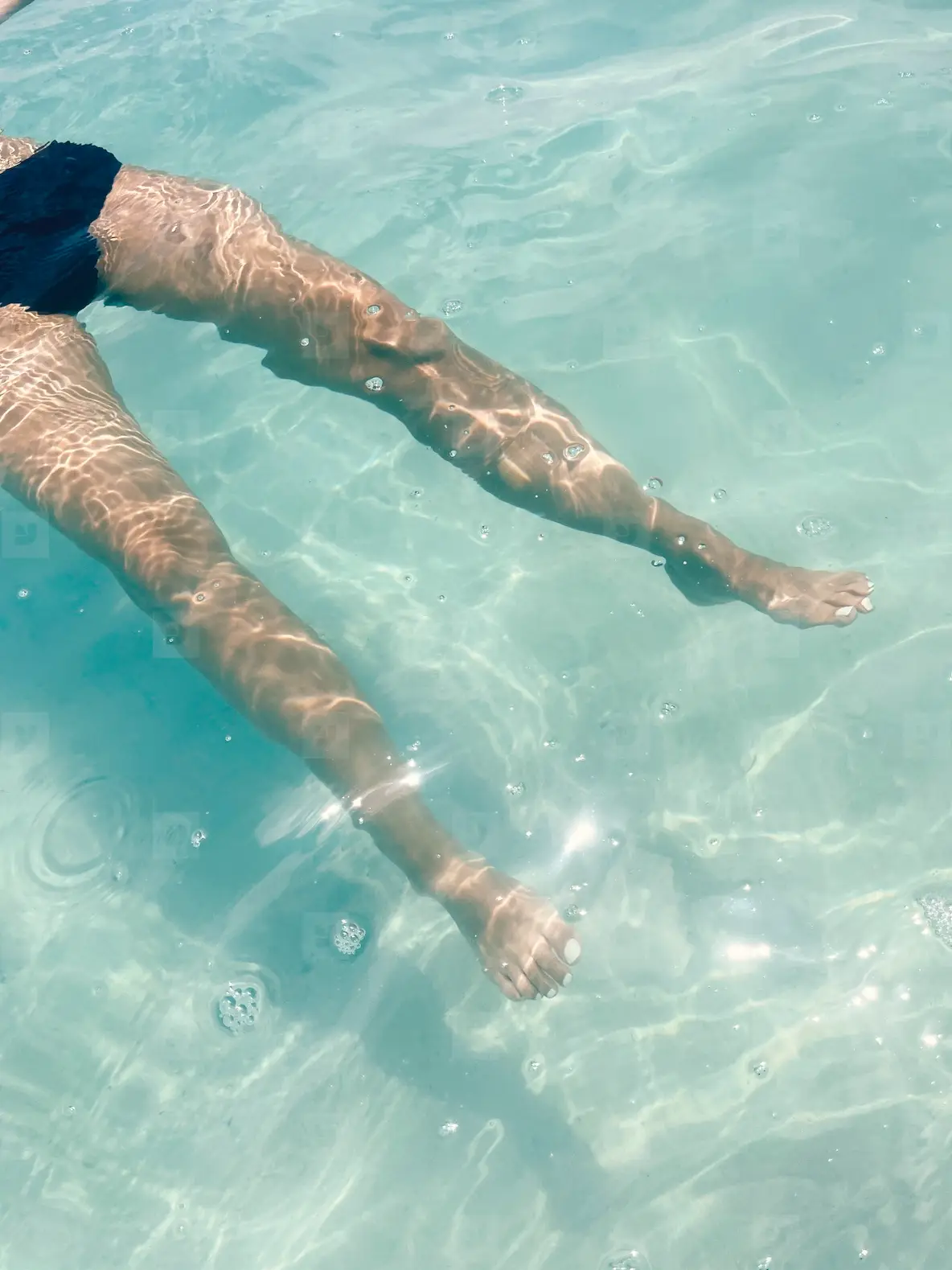 Legs of an unrecognizable woman in transparent ocean water
