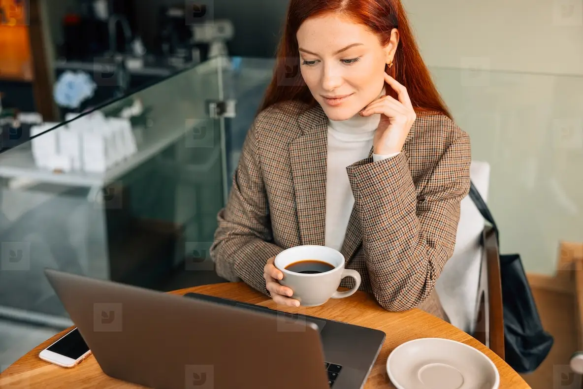 Businesswoman Holding A Cup Of Coffee And Looking At Laptop While ...