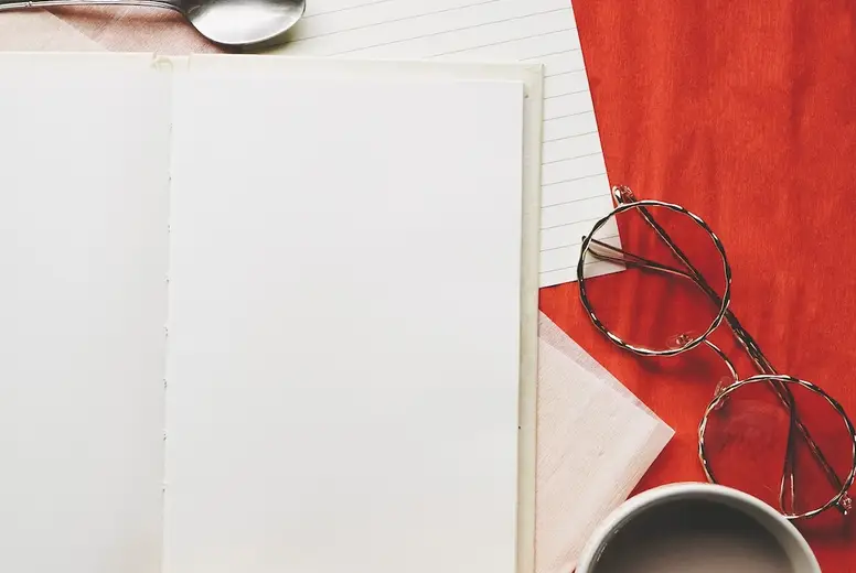 Colorful flat lay of an open diary surrounded by common objetcs
