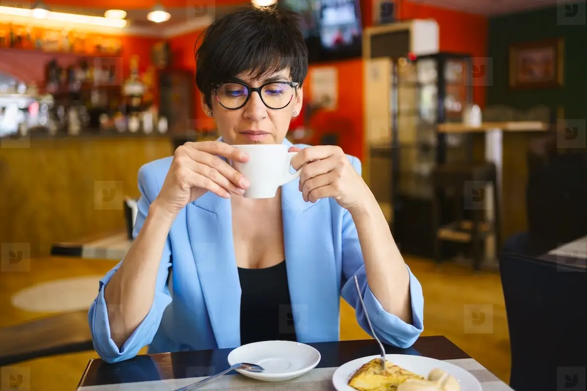 Calm middle aged woman enjoying hot coffee in cafe