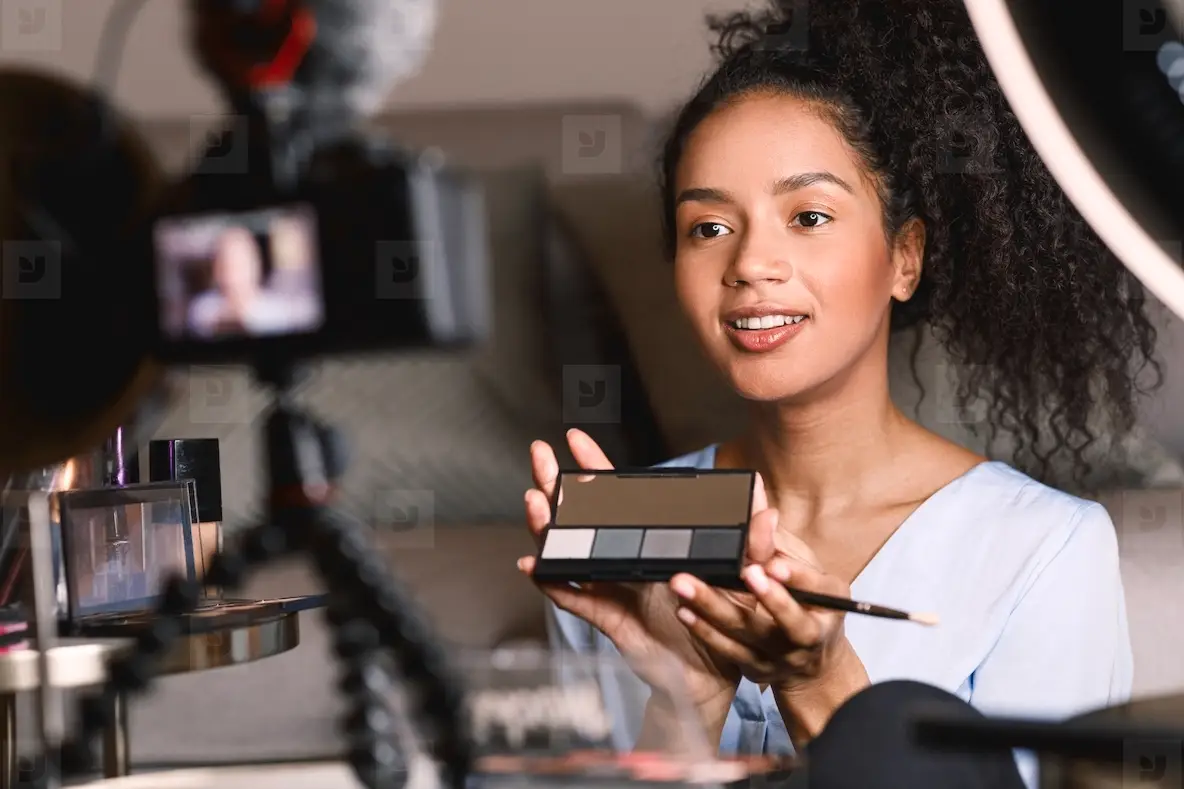 Young influencer making makeup tutorial while sitting in front of a camera