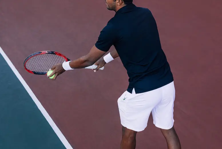 Tennis player with a racket ready to serve a tennis ball standing at the baseline