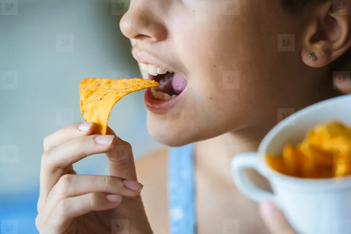Anonymous girl about to eat yummy nacho chip at home