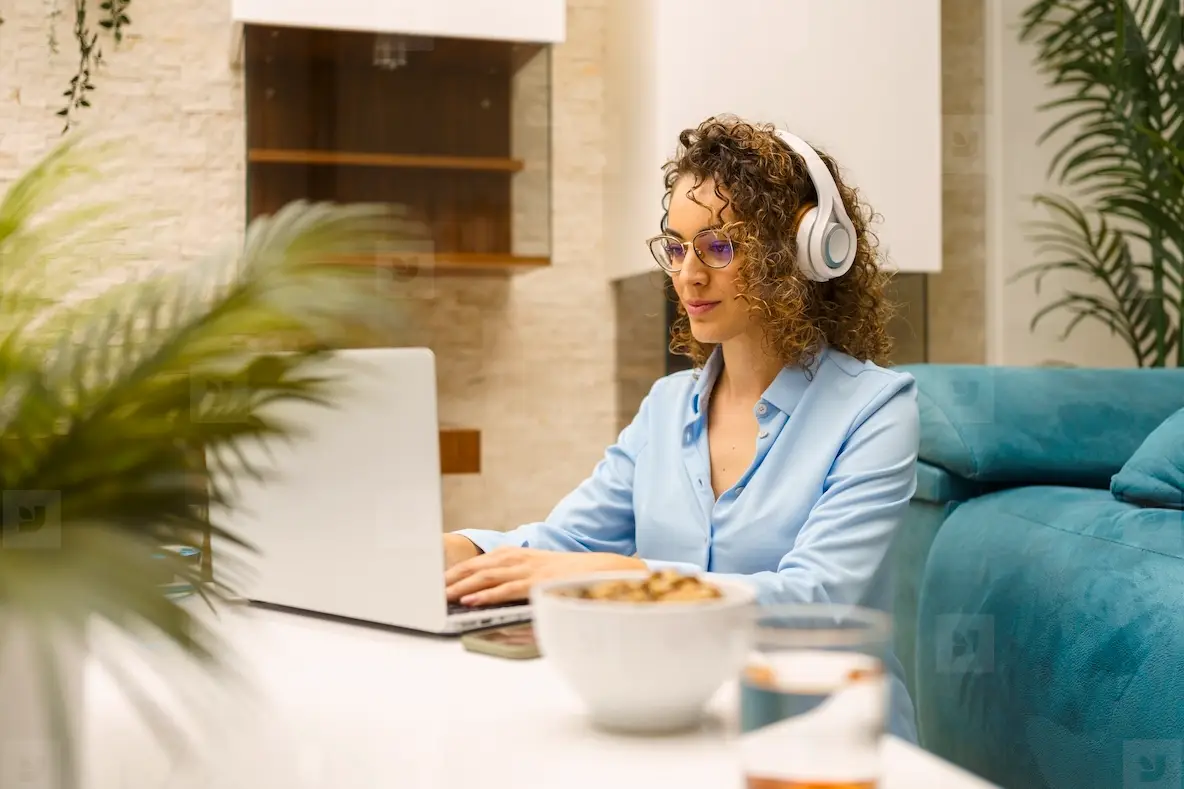 Positive Woman In Headphones Typing On Laptop While In Living Room ...