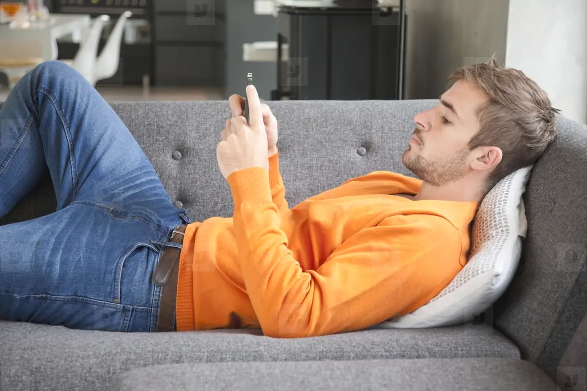 Man Lying on Sofa Using Smartphone
