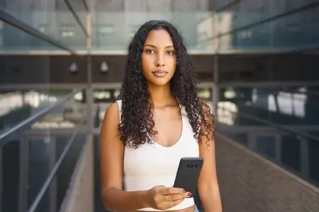 A confident young woman with a smartphone in a vibrant city  showcasing style and creativity