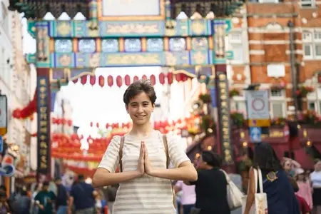 Cheerful teenage girl enjoying in Chinatown  posing with his hands clasped together as if meditating
