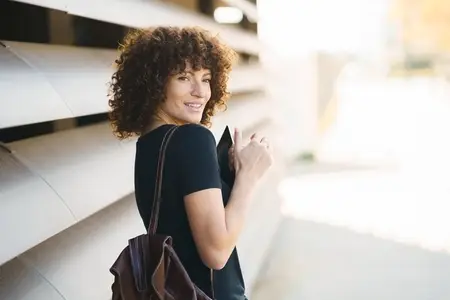 A Smiling Woman Sporting Curly Hair in a Bustling Urban Setting  Radiating Joy and Style
